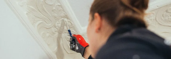 Person streicht Stuckleiste mit Pinsel